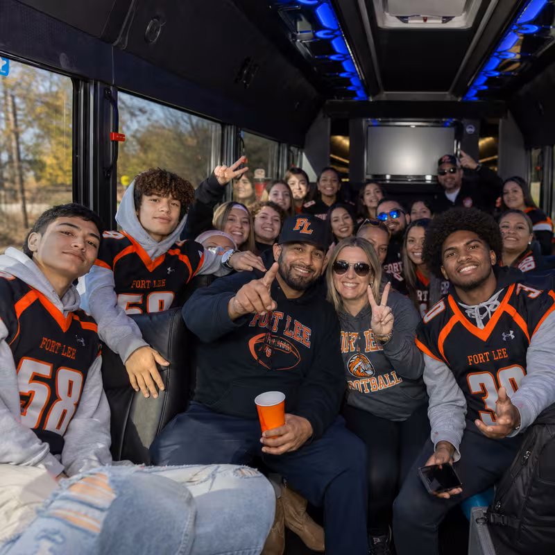 Group boarding a white charter bus for Sporting Event Transportation transportation in Fort Lee